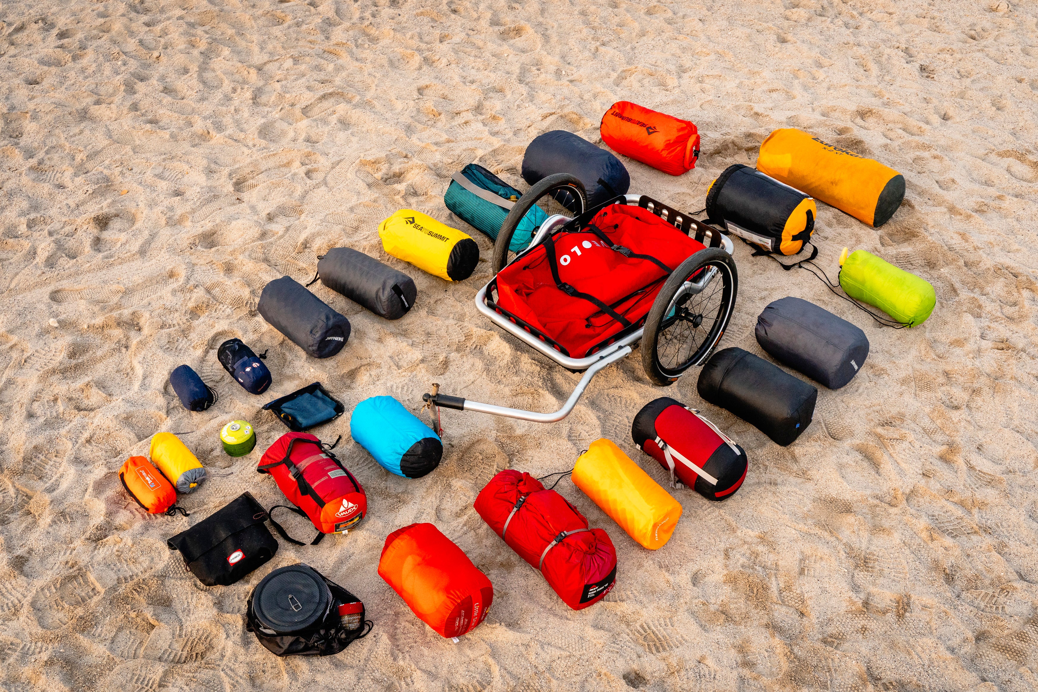 VEOLO Anhänger mit zusammengefalteter Fahrradanhänger-Tasche am Strand umringt von Gepäck